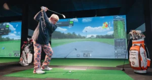 John Daly swinging at an X-Golf simulator while showing how to increase your smash factor.
