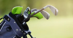 Close-up of a golf bag with shiny clubs and bright green headcovers