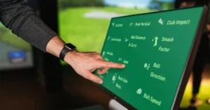 A golfer interacts with a touchscreen displaying performance metrics like ball speed, smash factor, and club path—highlighting how detailed stats answer the question: do golf simulators improve your game?