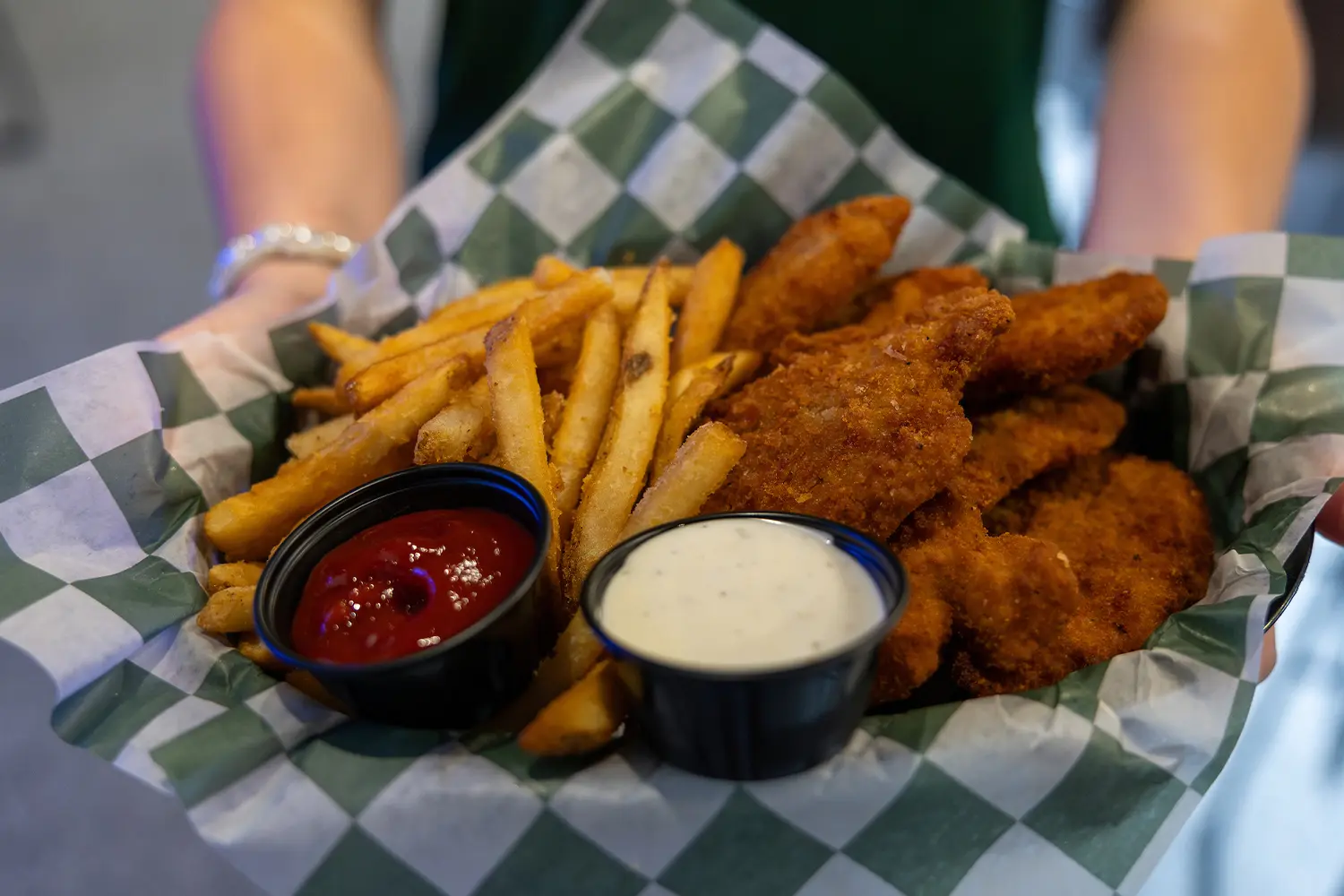 Basket of crispy chicken tenders with fries, served with ketchup and ranch dipping sauces.