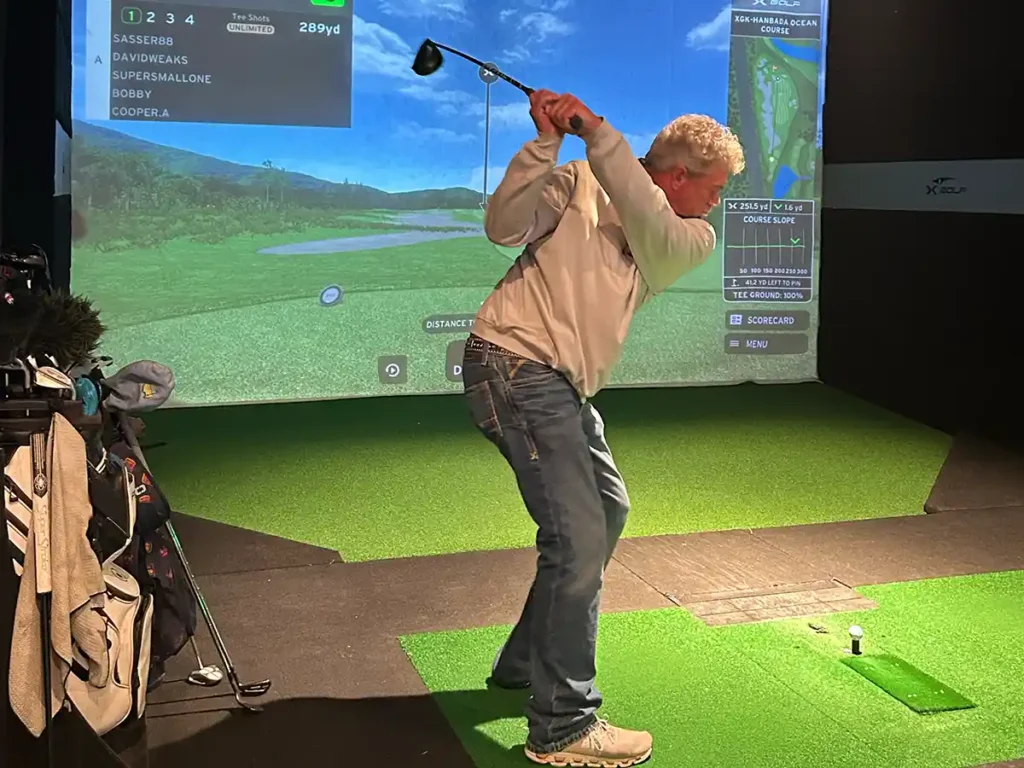 League competitor at the top of his backswing with a 289-yard drive shown on the simulator leaderboard.