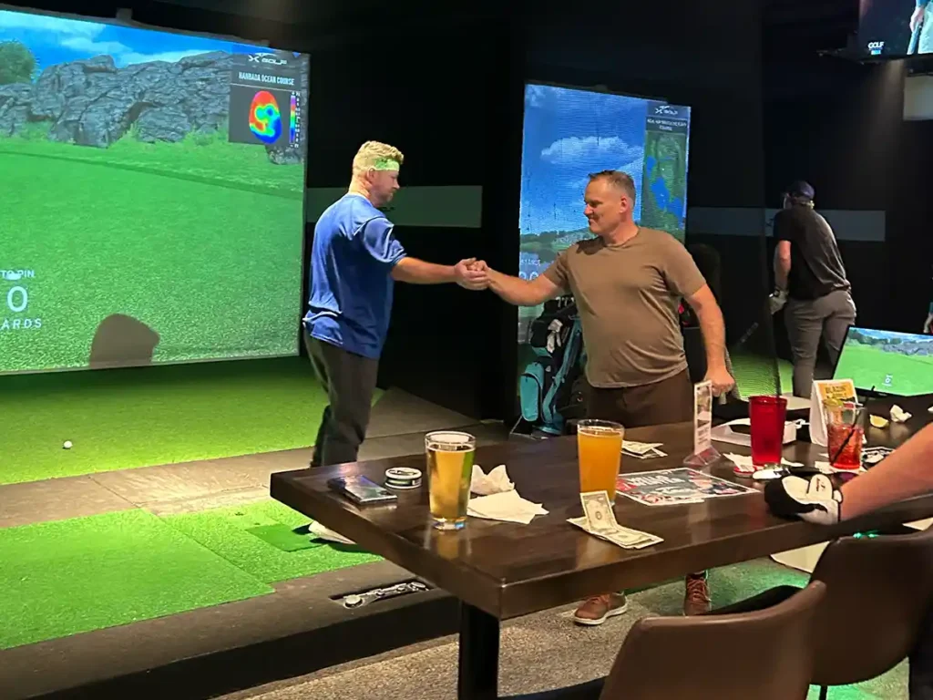 League players shake hands between bays with drinks and cash on the table during friendly competition.